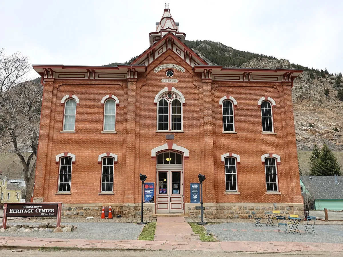 The red-brick 1874 Georgetown public school on Taos Street, now the Old School, with its earlier Georgetown Heritage Center sign out front, in May 2024